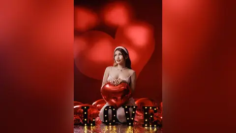 Young woman in white lace outfit holding a red heart balloon against a romantic red background for Valentine's Day.