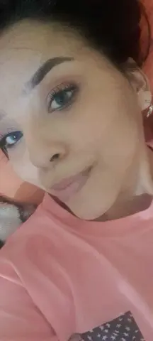 emilyywillis wearing a pink t-shirt and looking into the camera with a slight smile.