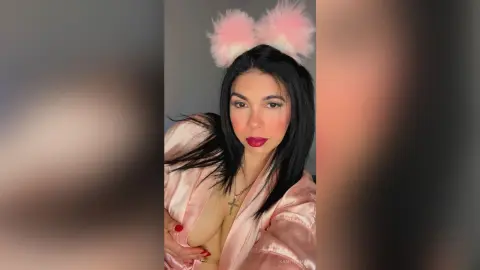 Young woman in a pink satin robe and fuzzy bunny ears posing with a glamorous makeup look.