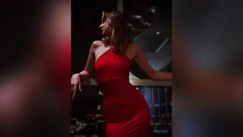 InaStark poses in a tight red dress against a dark background.