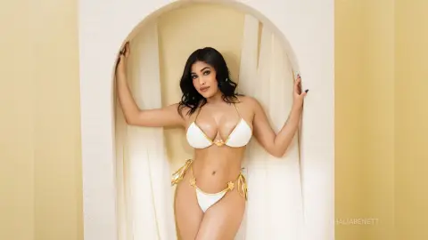 Curvy woman in a white bikini posing in a sunlit arched doorway for a summer fashion look.