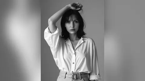 Elegant woman in a white button-down shirt posing in a minimalist studio setting, black and white portrait.