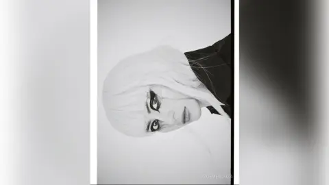 Moody black and white portrait of a blonde woman with dramatic eye makeup looking into the camera.