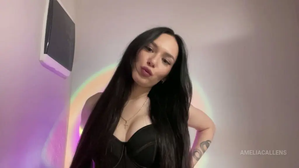 AmeliaCallens poses in a white long-sleeve top with her long black hair down and gold hoop earrings.