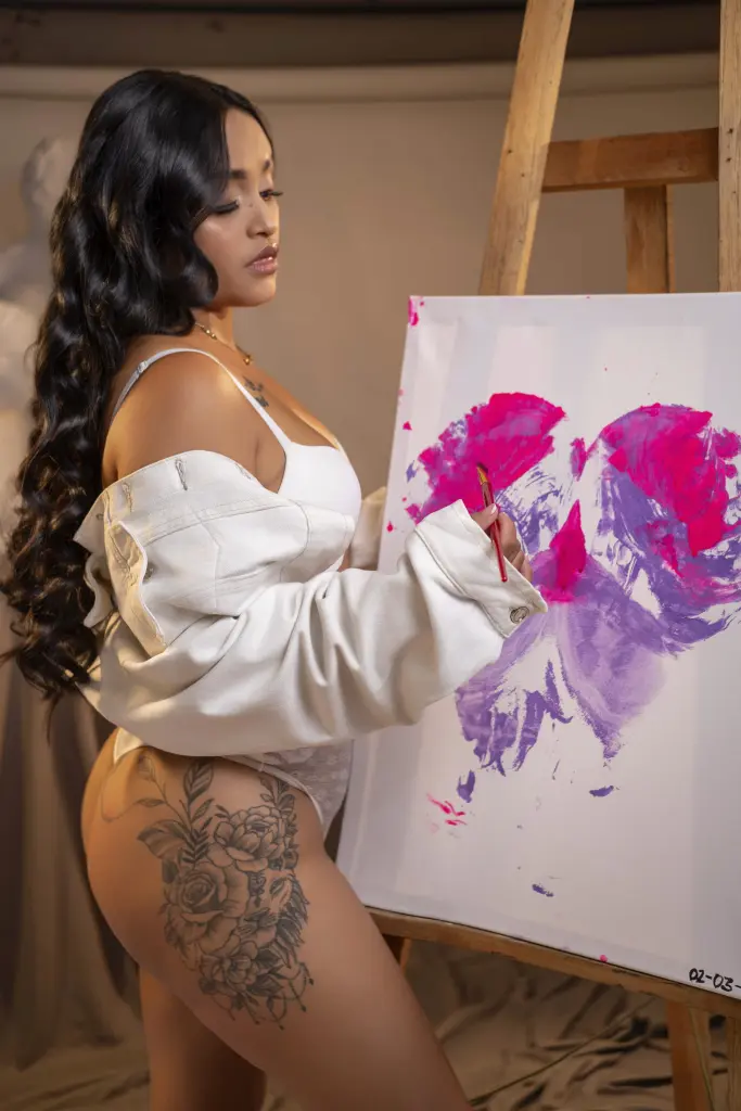 susan_bigass wears white lingerie while posing on a bed with long wavy dark hair.