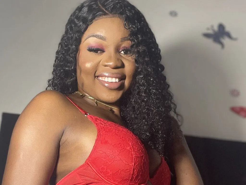 ElenaJax smiles while wearing a pink floral lace camisole and a thin gold choker necklace.