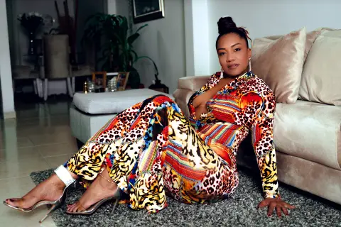 Stylish woman in a colorful leopard print jumpsuit relaxing on a living room floor.