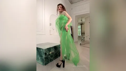 SabrinaBauer — SabrinaBauer stands in a white room wearing a sheer lime green dress that reveals her legs.