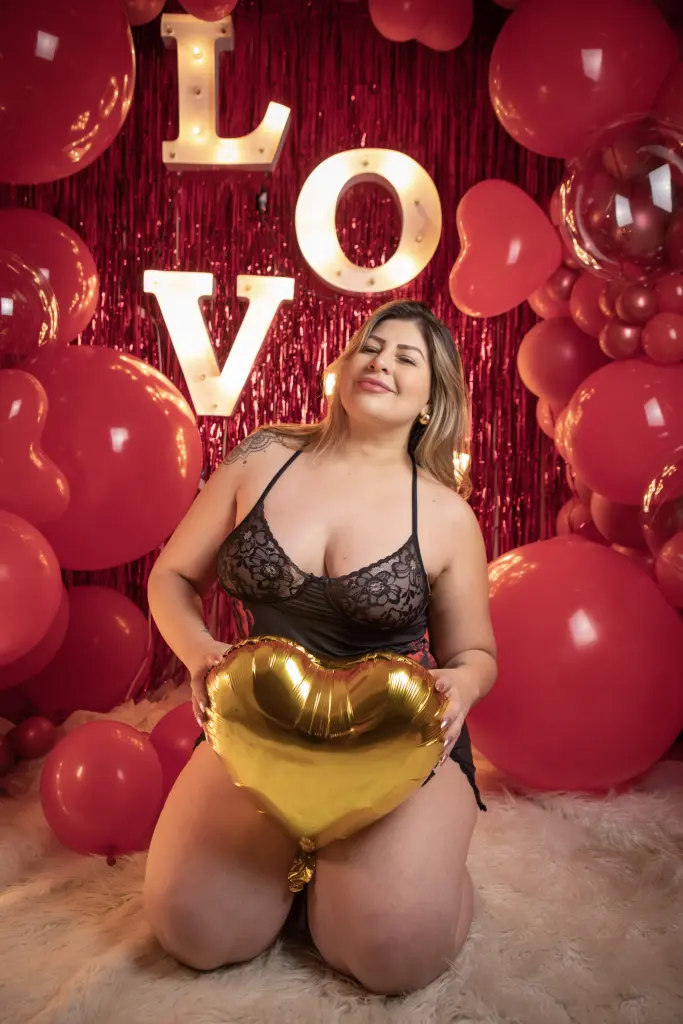 Blonde woman in a black bra sitting in a bedroom with colorful mood lighting.