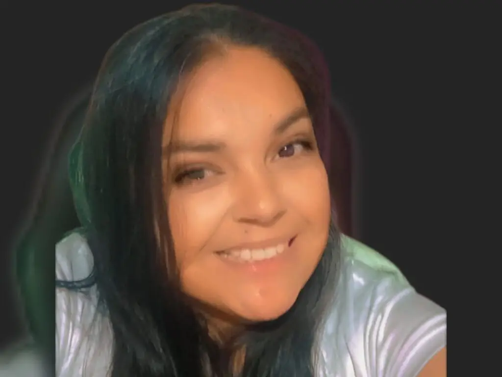 AlexaAurora smiles directly at the camera with her long dark hair falling over her shoulders.