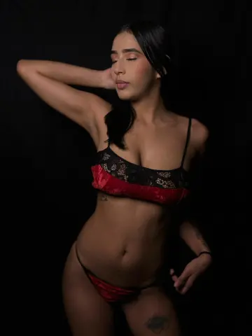 Young woman in red and black lace lingerie posing against a dark background with a moody, elegant vibe.