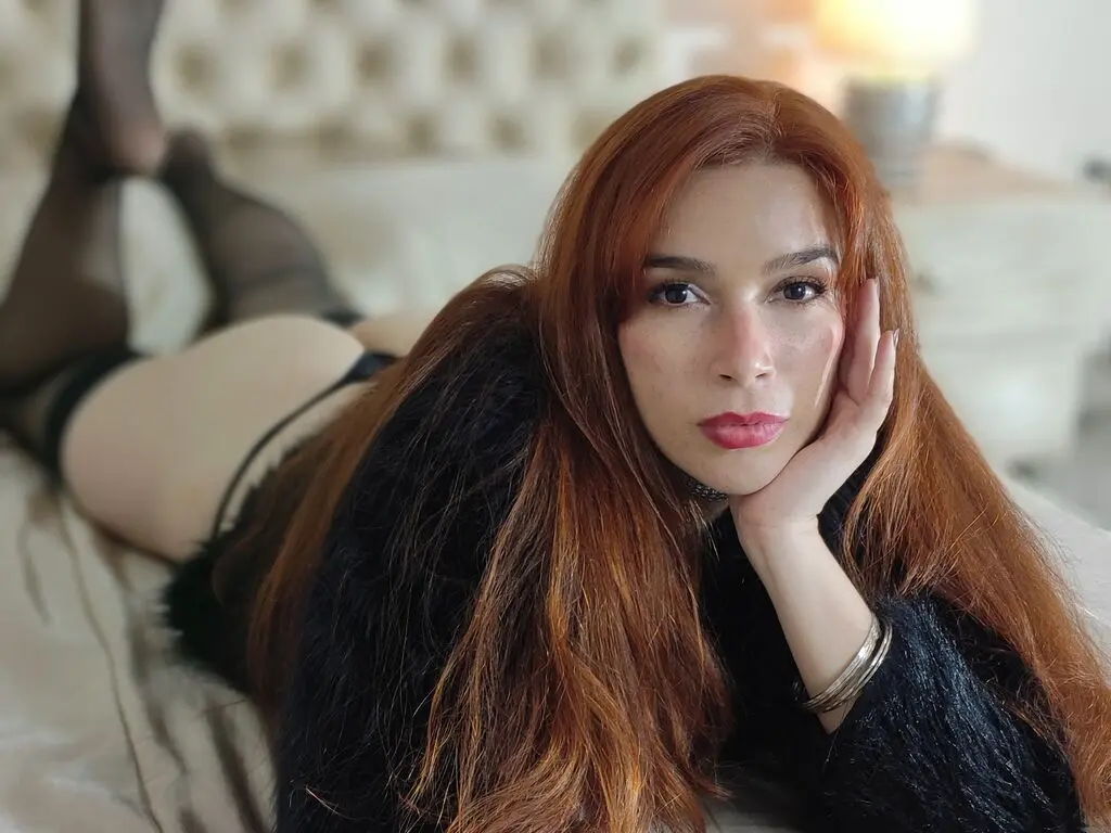 Redheaded woman in black lingerie relaxing on a bed with a dreamy, intimate mood.