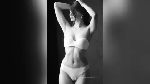 Elegant woman in white lingerie posing gracefully in a moody black and white studio portrait.