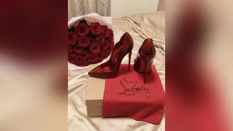AlienaMoore — AlienaMoore displays a bouquet of red roses next to red Christian Louboutin high heels on a bed.