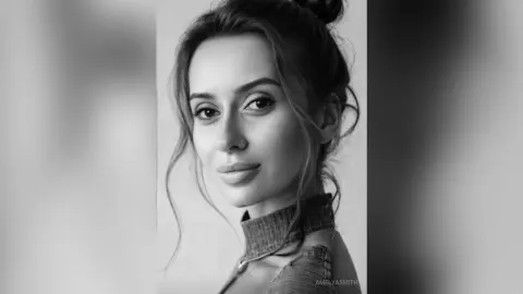 Serene black and white portrait of a woman with a messy bun wearing a textured turtleneck sweater.