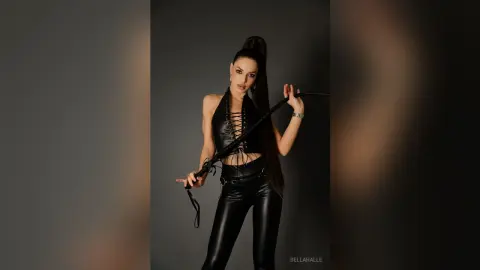 Stylish woman in a black lace-up halter top and leather pants posing confidently against a dark studio background.