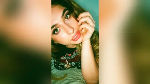 IrinaMolkova looks at the camera with a soft smile, resting her chin on her hand while wearing a black graphic t-shirt.