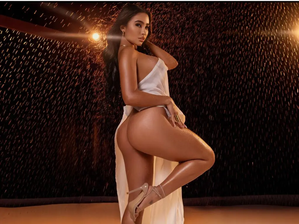 Glamorous woman in a white silk dress posing under golden rain lights for a moody, elegant photoshoot.