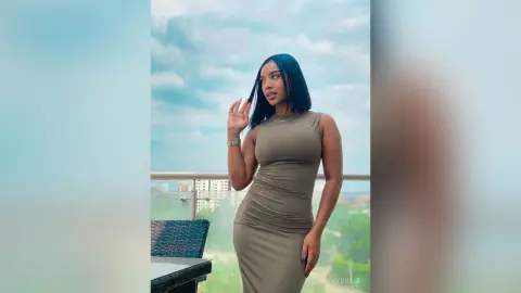 Elegant woman in a tight olive green midi dress posing on a balcony against a cloudy sky.