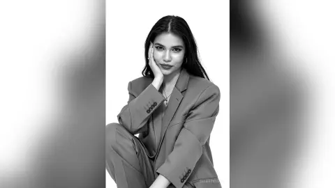Elegant woman in a professional blazer posing for a sophisticated black and white studio portrait.