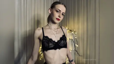 Elegant woman in black lace lingerie posing against a soft-lit textured background with a moody atmosphere.