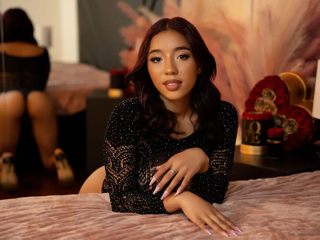 Beautiful woman in a black lace top relaxing on a pink velvet bed in a romantic, moody setting.