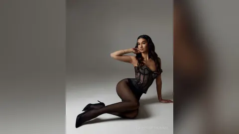 CatherineThomase — CatherineThomase poses in black lace lingerie and sheer black tights against a grey background.