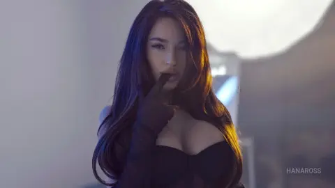 Beautiful woman with long dark hair wearing black gloves in a moody, dimly lit indoor setting.