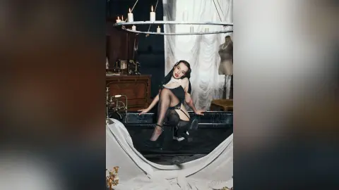 Elegant woman in black lingerie and stockings sitting in a vintage bathtub under a candlelit chandelier.