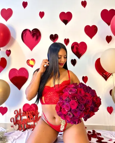 Woman in red lace lingerie holding a rose bouquet against a romantic heart balloon background.