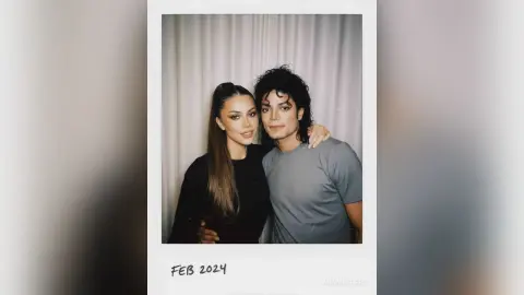 Polaroid of a smiling woman in a black top and Michael Jackson in a grey t-shirt posing together indoors.