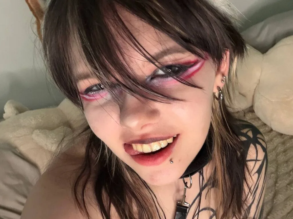 BettieDaryanl smiles at the camera with pink eye makeup and a black leather choker.