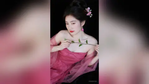 Elegant woman in a pink flowing gown holding a green branch against a dark background for a romantic mood.