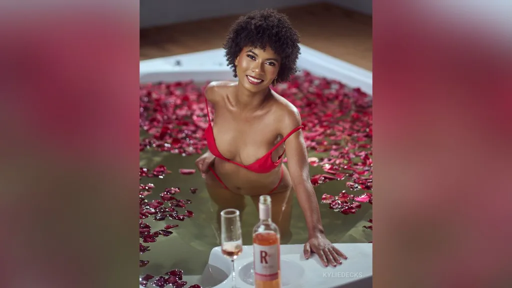KylieDecks — KylieDecks smiles in a white bathtub filled with water and red rose petals, wearing a tiny red bikini.