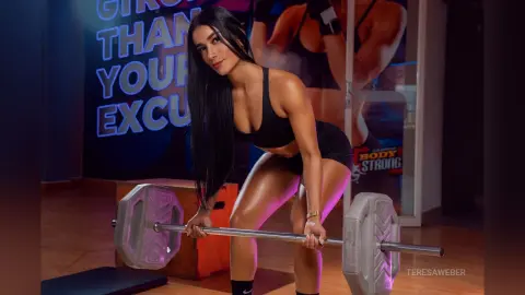 Athletic woman in black gym wear performing deadlifts in a modern fitness studio with a focused mood.