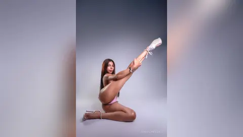 Athletic woman in pink lingerie posing gracefully in a studio setting with a minimalist mood.