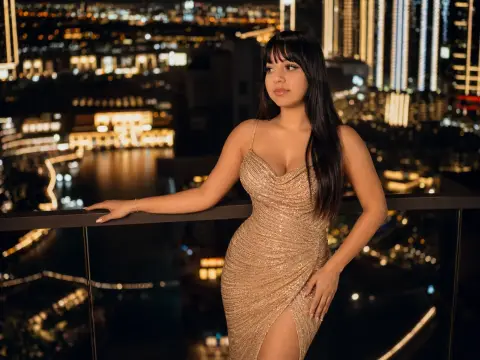 Glamorous woman in a gold sequin cocktail dress posing on a rooftop balcony overlooking a glowing city skyline.