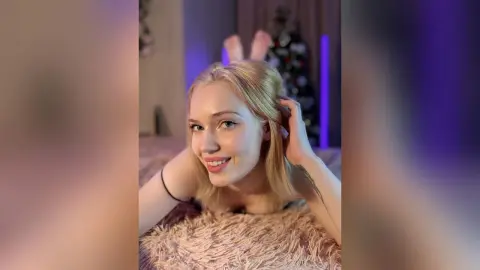 Smiling blonde woman in a black top relaxing on a cozy shag rug in a room with purple ambient lighting.
