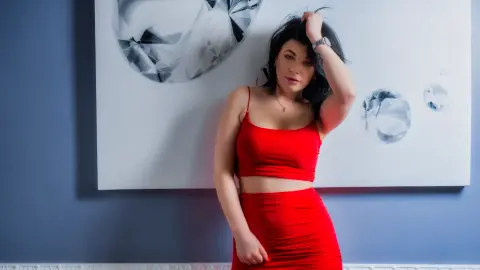 Elegant woman in a red cocktail dress posing against abstract wall art in a modern blue room.