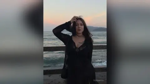 Young woman in a black lace outfit posing at the beach during a moody sunset.