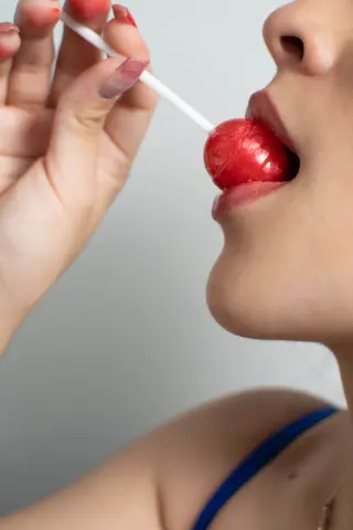 Susanmaeda licks a red lollipop with her mouth open, looking up in a close-up shot.