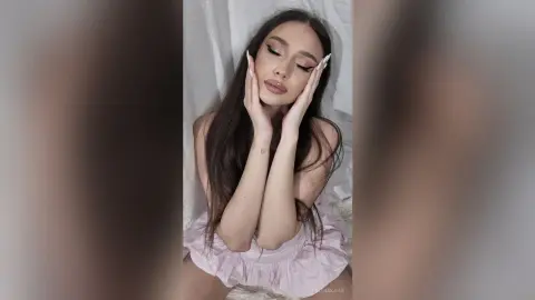 Glamorous woman in a pink ruffled dress with soft makeup posing against a white fabric backdrop.