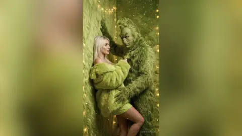 JessycaPage wears a fuzzy green outfit while posing closely with a tall, hairy green creature in a sparkly green room.