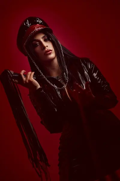 AfroditaDior poses in a red bodysuit and fur coat against a red curtain backdrop.