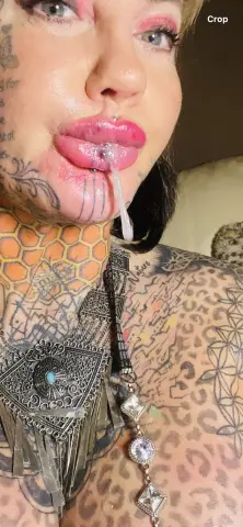 Tattooed woman with pink makeup and bohemian silver jewelry in a close-up portrait.