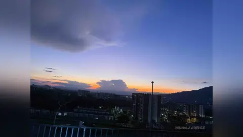 Serene twilight cityscape view with orange sunset clouds over a dark urban skyline at dusk.