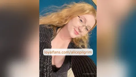 Smiling blonde woman with glasses in a black sparkly top relaxing against a blue background.
