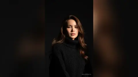 Elegant woman in a black ribbed turtleneck sweater posing against a dark moody background.