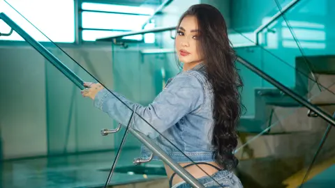 Young woman in a denim jacket posing on a modern glass staircase with a serene mood.