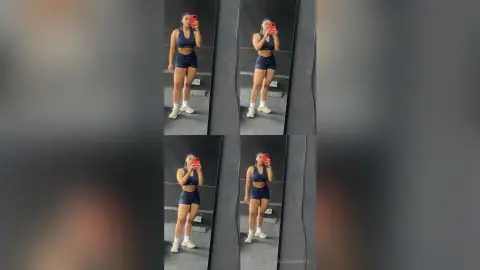 Fit woman in navy blue sports bra and shorts taking a mirror selfie in a modern gym setting.